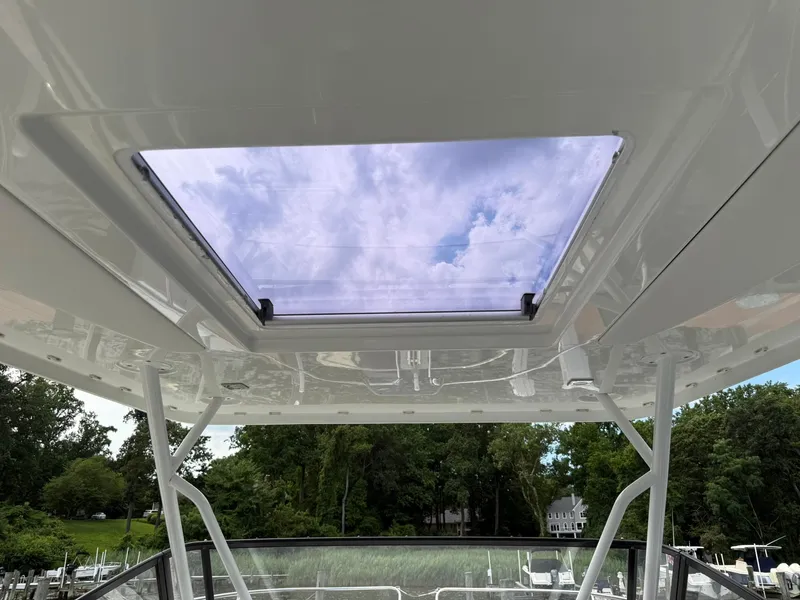 Slide: The Image of 2018 Jeanneau Leader 10.5 boat with open sunroof, showcasing sky and trees. - 12