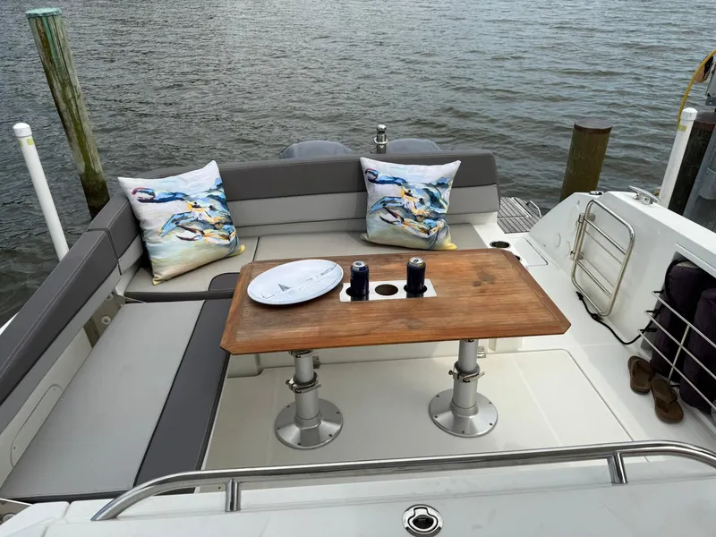 Slide: The Image of Cozy seating area on 2018 Jeanneau Leader 10.5 boat with wooden table and decorative pillows. - 13