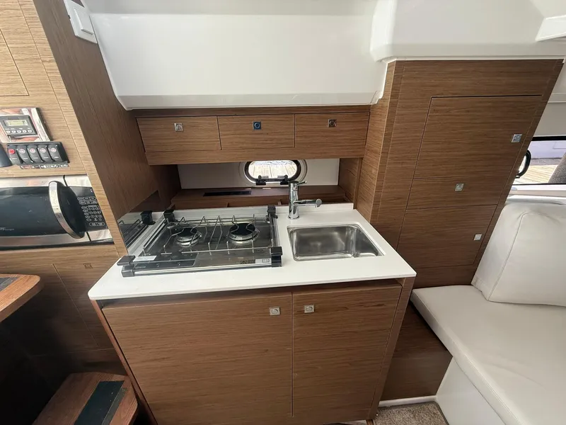 Slide: The Image of 2018 Jeanneau Leader 10.5 yacht kitchen with stove, sink, and wood cabinetry. - 20