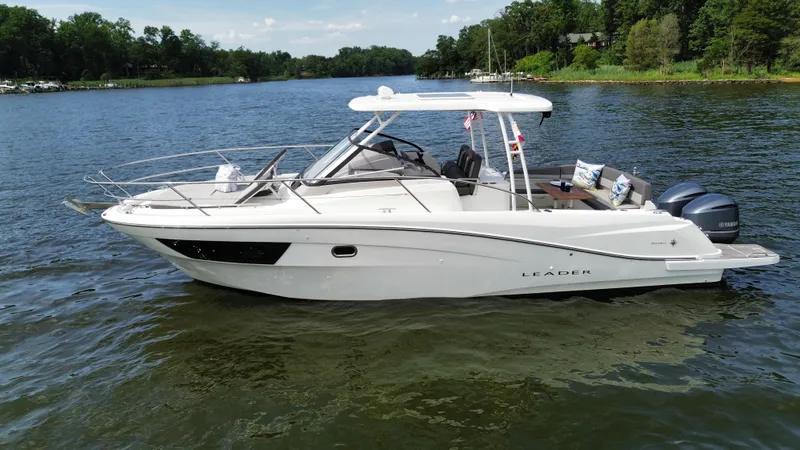 Slide: The Image of 2018 Jeanneau Leader 10.5 boat on a serene lake with lush green shoreline. - 6