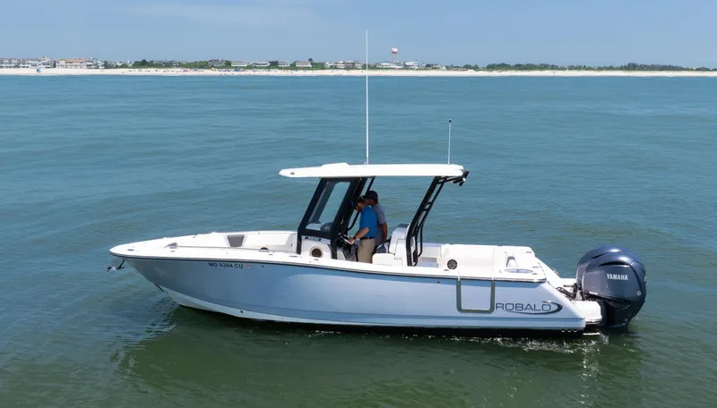 Slide: The Image of 2023 Robalo R270 Center Console boat on calm ocean near sandy shoreline. - 13