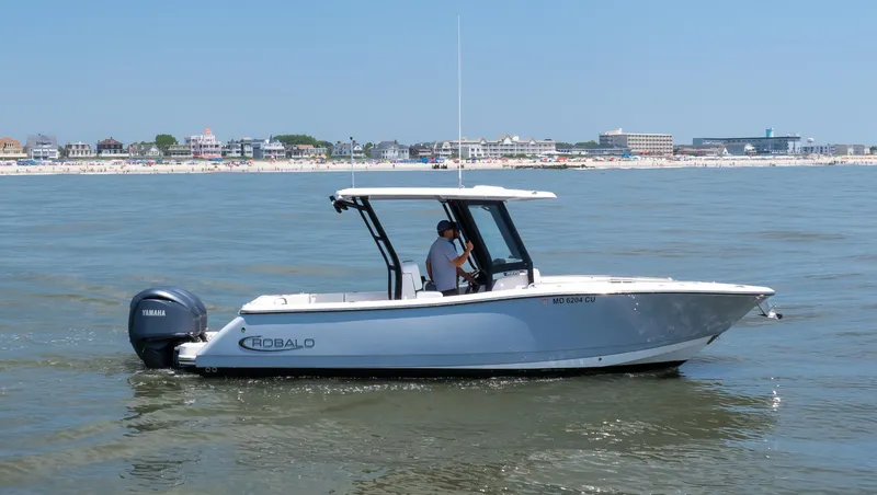 Slide: The Image of 2023 Robalo R270 Center Console boat cruising near a coastal town. - 15