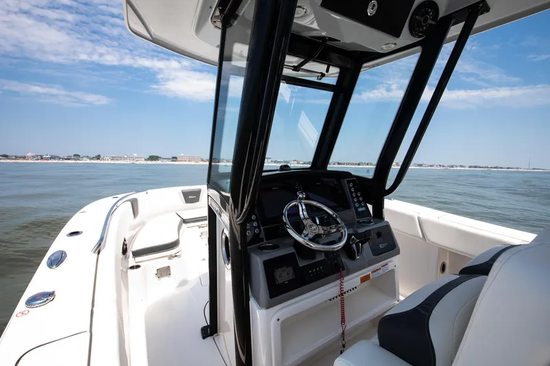 Slide: The Image of 2023 Robalo R270 Center Console boat interior with steering wheel, on calm water. - 4