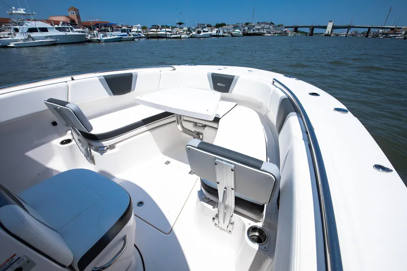Slide: The Image of 2023 Robalo R270 Center Console boat interior with seating and table, docked in a marina. - 7
