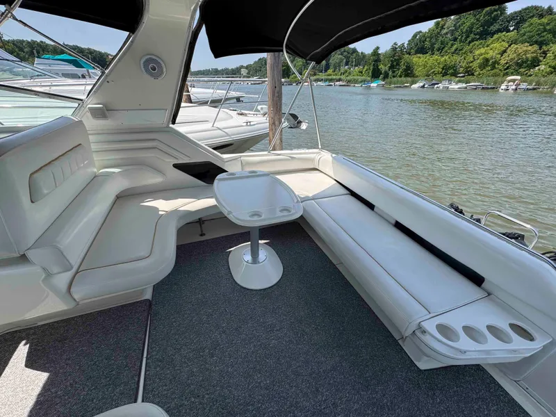 Slide: The Image of 1995 Sea Ray 400 Express Cruiser interior with seating and table, docked on a scenic river. - 10