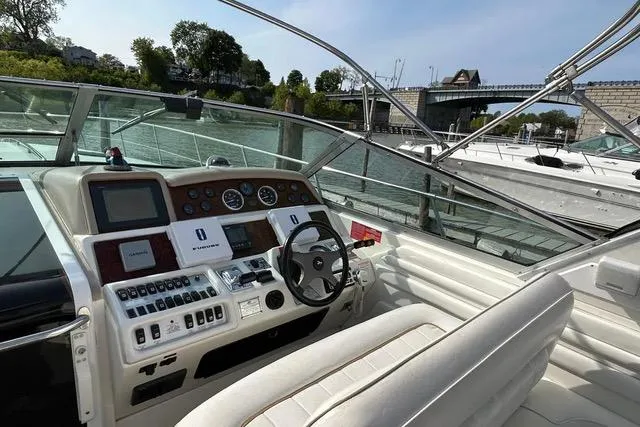 Slide: The Image of 1995 Sea Ray 400 Express Cruiser helm with controls and gauges, docked near a bridge. - 11