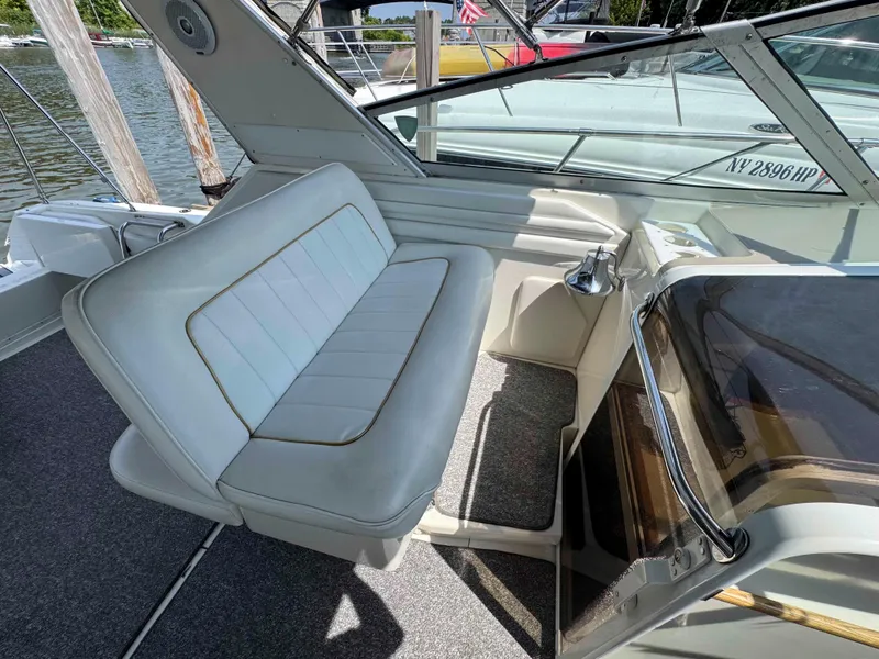 Slide: The Image of 1995 Sea Ray 400 Express Cruiser interior with white seating and helm, docked by the water. - 14