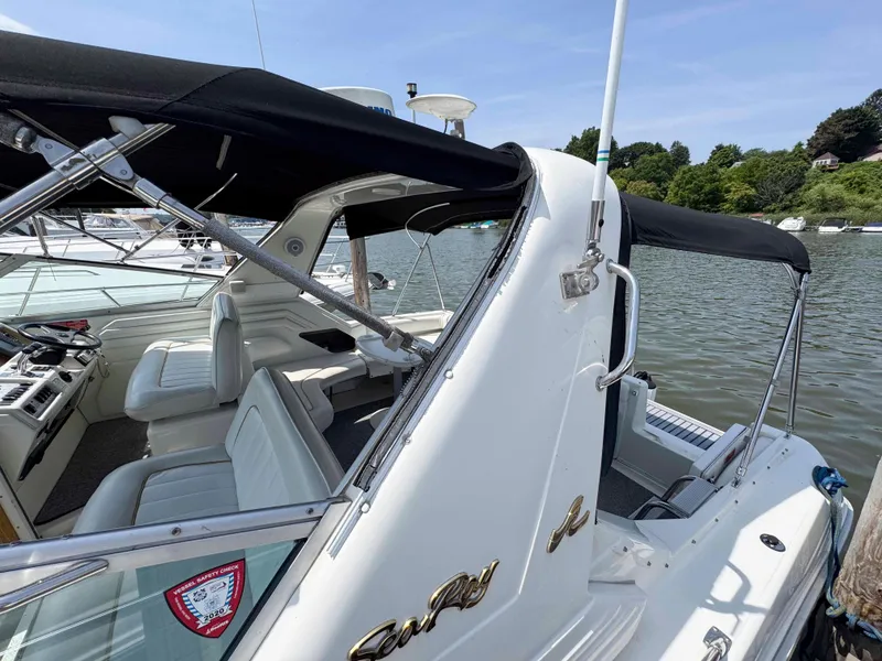 Slide: The Image of 1995 Sea Ray 400 Express Cruiser with black canopy, docked on a calm river. - 16