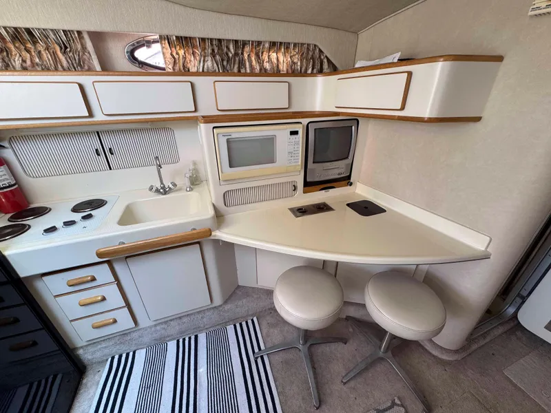 Slide: The Image of 1995 Sea Ray 400 Express Cruiser kitchen with stove, sink, microwave, and seating area. - 20