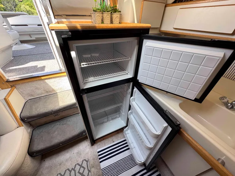 Slide: The Image of Interior of 1995 Sea Ray 400 Express Cruiser with open fridge and steps. - 24
