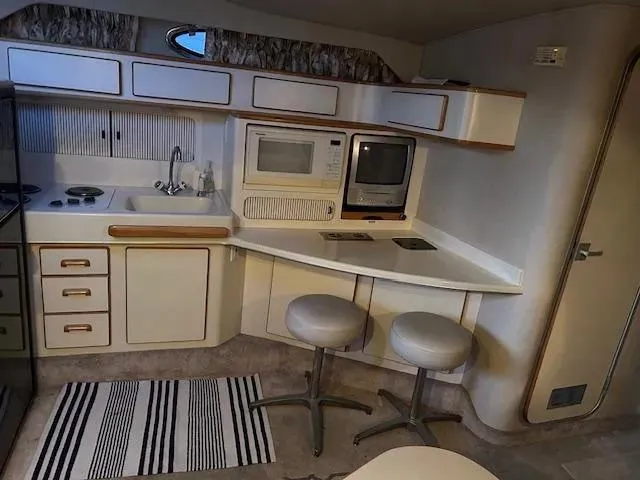 Slide: The Image of Interior of 1995 Sea Ray 400 Express Cruiser kitchen with appliances and seating. - 25