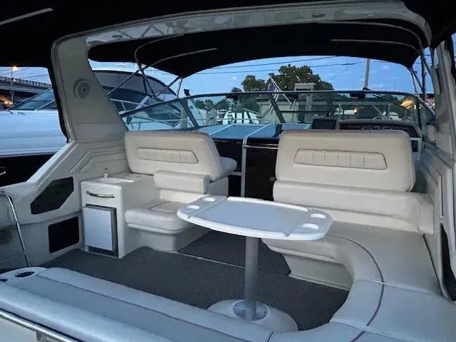 Slide: The Image of 1995 Sea Ray 400 Express Cruiser interior with white seating and table, under a canopy. - 6