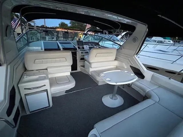 Slide: The Image of 1995 Sea Ray 400 Express Cruiser interior with white seating and table, docked at marina. - 9