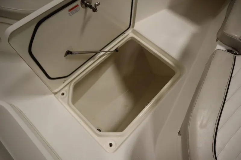 Slide: The Image of Open storage compartment on 2017 Mako 284 CC boat, featuring white interior and cushioned seating. - 19