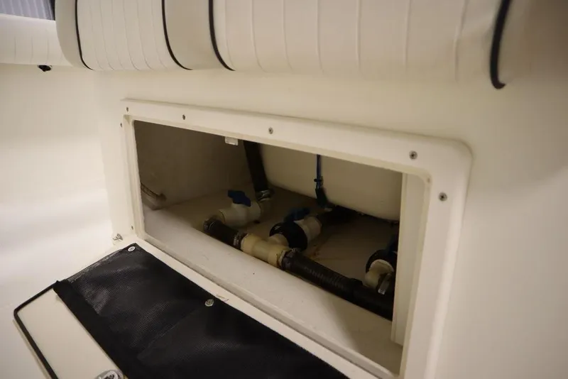 Slide: The Image of 2017 Mako 284 CC boat storage compartment with visible plumbing and seating. - 44