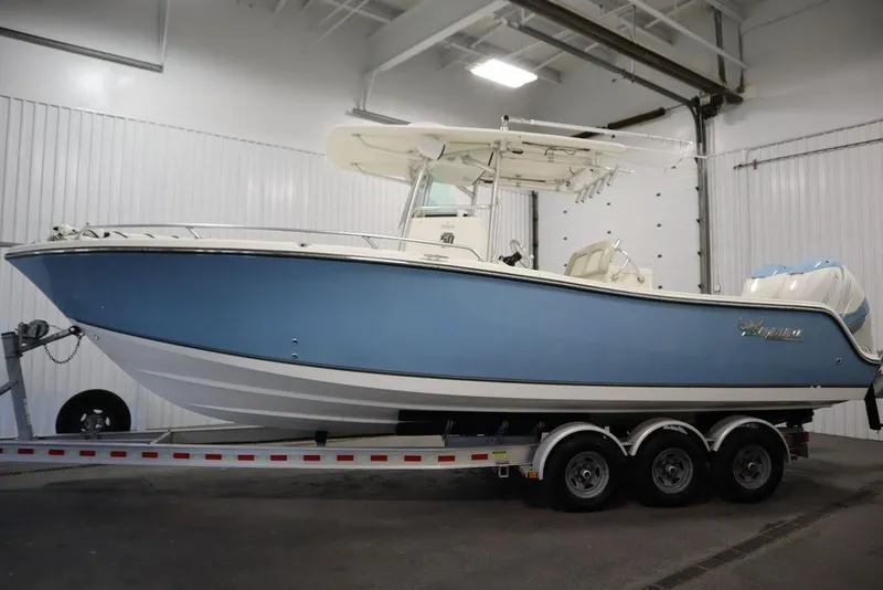 Slide: The Image of 2017 Mako 284 CC boat in a garage, blue hull, on a trailer. - 9