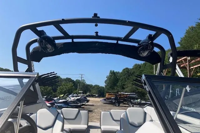 Slide: The Image of 2021 Yamaha Boats 252XE interior with wakeboard tower and seating, parked outdoors. - 18