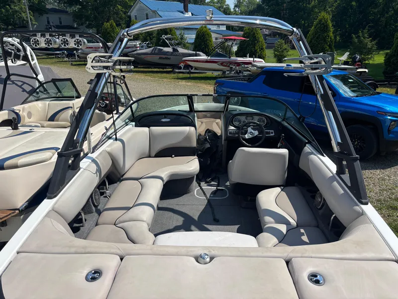 Slide: The Image of 2011 Malibu 21 vRide boat interior with seating and steering wheel, parked outdoors. - 4