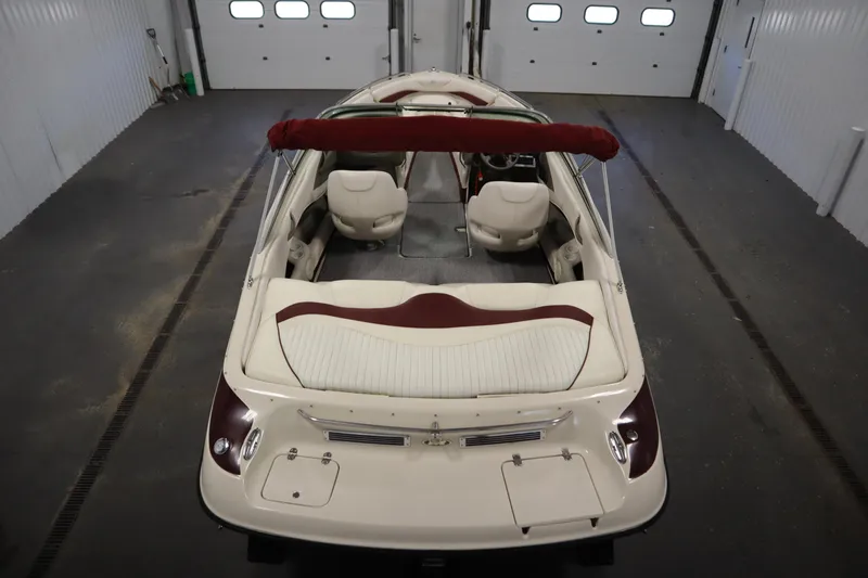 Slide: The Image of 2003 Crownline 202 BR boat in a garage, featuring white and maroon interior. - 10