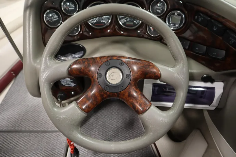 Slide: The Image of Steering wheel of a 2003 Crownline 202 BR boat with wood accents and dashboard controls. - 22