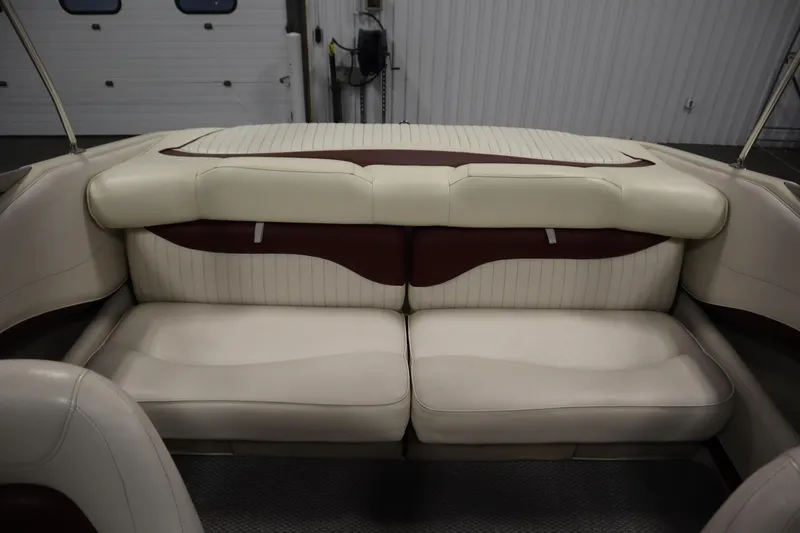 Slide: The Image of 2003 Crownline 202 BR boat interior with beige and maroon seating in a garage setting. - 43