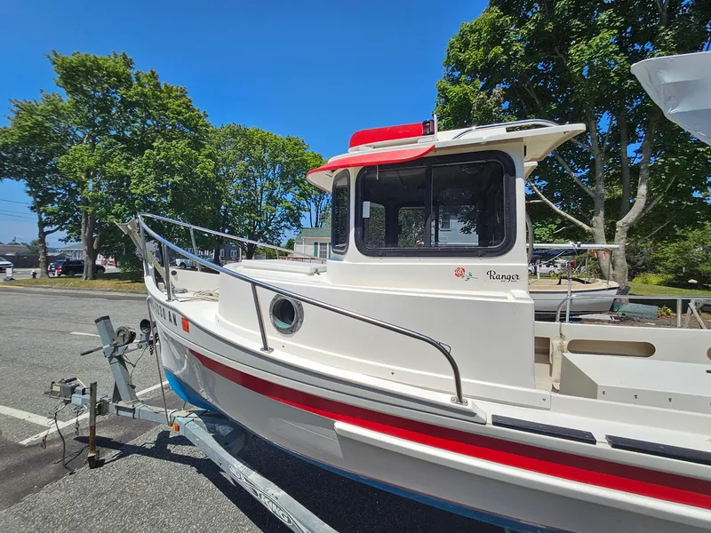 Slide: The Image of 2005 Ranger Tugs R-21 boat on trailer, parked outdoors under clear blue sky. - 1