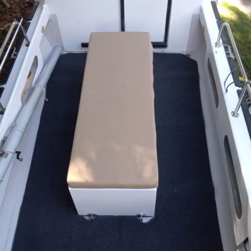 Slide: The Image of 2005 Ranger Tugs R-21 interior with beige cushioned seating and blue carpet. - 24