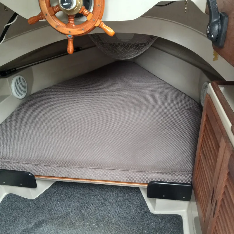 Slide: The Image of 2005 Ranger Tugs R-21 cabin interior with wooden steering wheel and cushioned berth. - 7