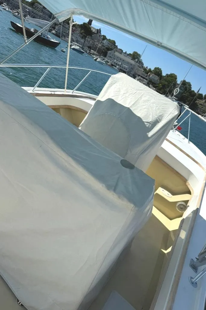 Slide: The Image of 1986 Dusky 26 Custom boat interior with covered seating, docked by a scenic waterfront. - 2