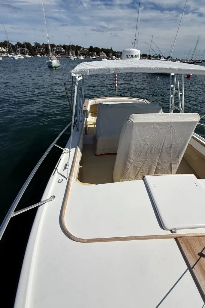 Slide: The Image of 1986 Dusky 26 Custom boat on water, featuring covered seating and Garmin equipment. - 9