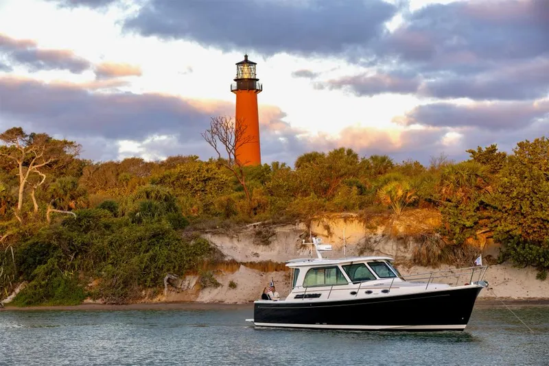 The Image of 2026 Back Cove 372 boat near a scenic lighthouse and lush greenery. - 1