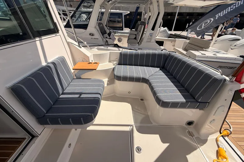 Slide: The Image of 2026 Back Cove 372 boat interior with striped seating and small wooden table. - 23
