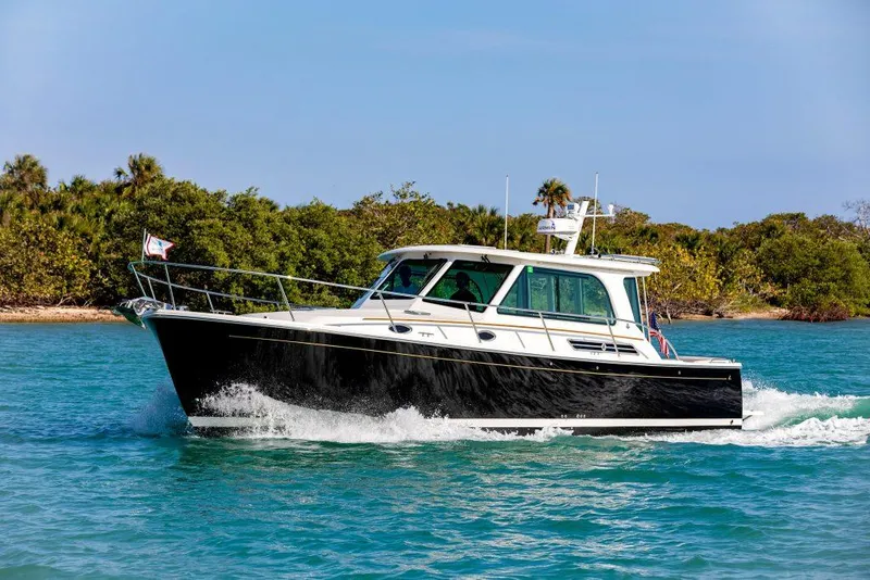 Slide: The Image of 2026 Back Cove 372 cruising on clear blue water near lush green shoreline. - 4