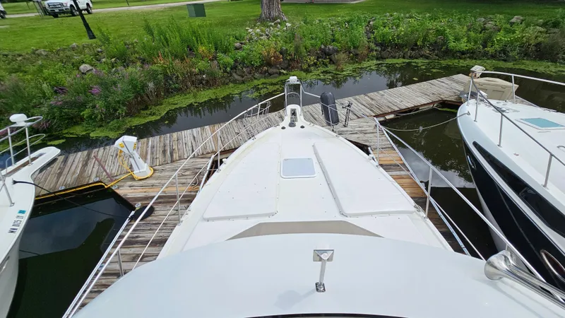 Slide: The Image of 1997 Carver 355 Motor Yacht docked at a wooden pier, surrounded by lush greenery. - 11