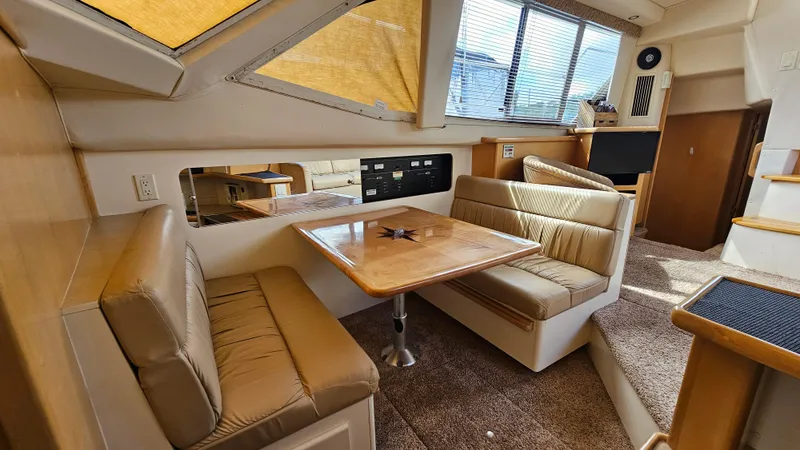 Slide: The Image of 1997 Carver 355 Motor Yacht interior with dining area, beige seating, and natural light. - 19