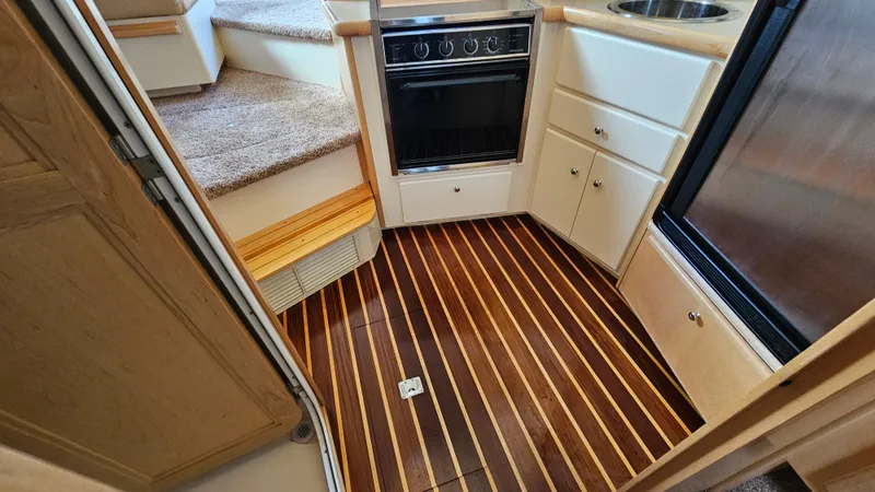 Slide: The Image of 1997 Carver 355 Motor Yacht kitchen with wood flooring, oven, and compact cabinetry. - 22