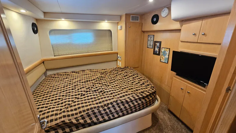 Slide: The Image of 1997 Carver 355 Motor Yacht bedroom with checkered bedding, wood cabinets, and wall art. - 28
