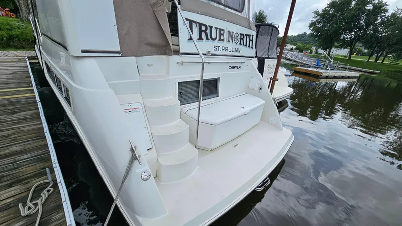 Slide: The Image of 1997 Carver 355 Motor Yacht docked, featuring rear deck and steps, labeled "True North." - 4