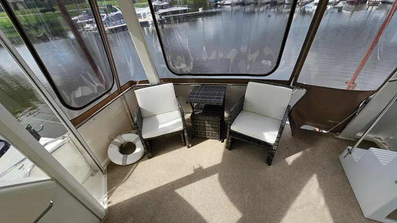 Slide: The Image of 1997 Carver 355 Motor Yacht interior with wicker chairs and table, overlooking marina. - 5