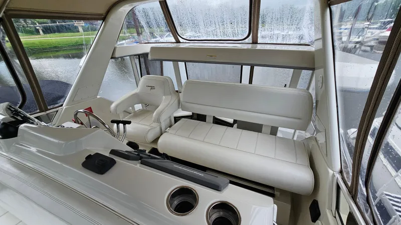 Slide: The Image of 1997 Carver 355 Motor Yacht interior with white seating and helm, overlooking marina. - 9