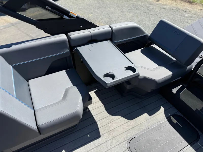 Slide: The Image of 2025 Manitou Explore Dual Engine boat interior with gray seating and foldable table. - 18