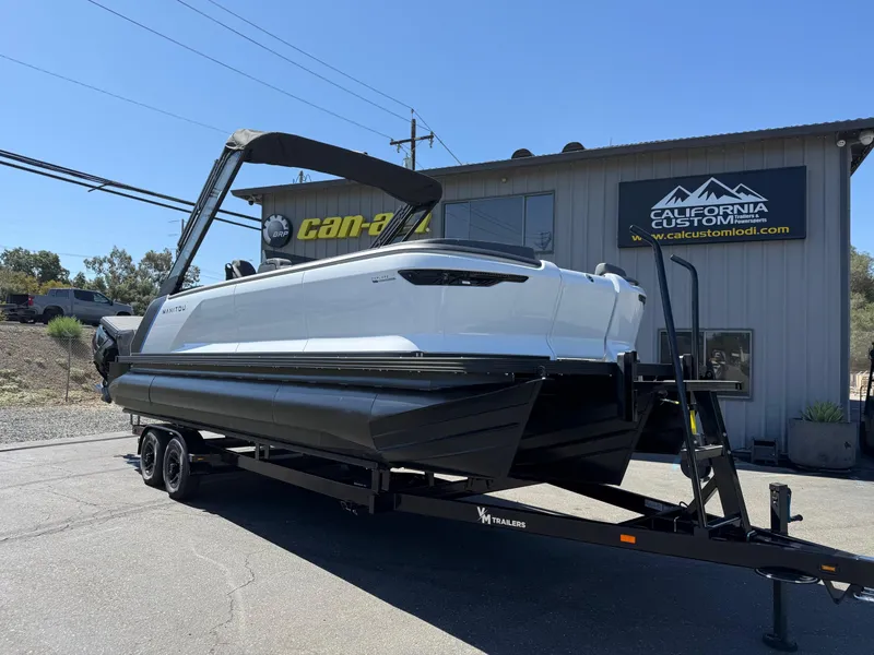 Slide: The Image of 2025 Manitou Explore Dual Engine boat on trailer at California Custom dealership. - 3