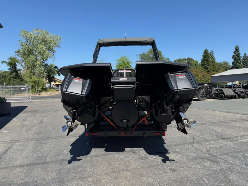 Slide: The Image of 2025 Manitou Explore Dual Engine boat with twin outboard motors, parked outdoors. - 5