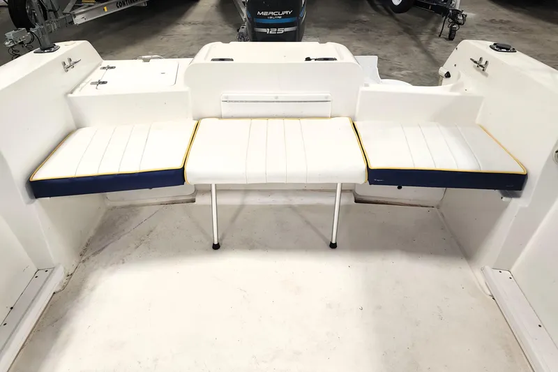 Slide: The Image of 1999 Campion Explorer 552 boat interior with white cushioned seating and Mercury engine. - 2