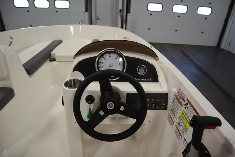 Slide: The Image of 2022 Bayliner E18 Element boat dashboard with steering wheel and gauges in a garage setting. - 18