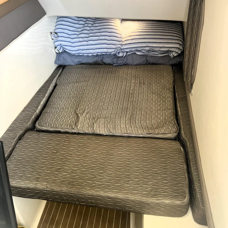 Slide: The Image of Cozy cabin bed in 2016 World Cat 320 DC boat with striped bedding. - 10