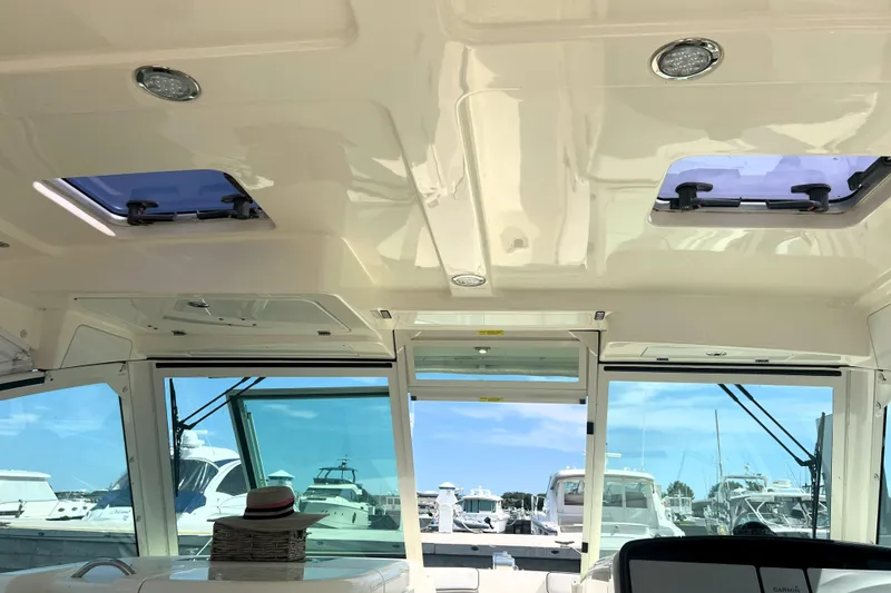 Slide: The Image of Interior view of 2016 World Cat 320 DC boat with sunroof and marina background. - 27