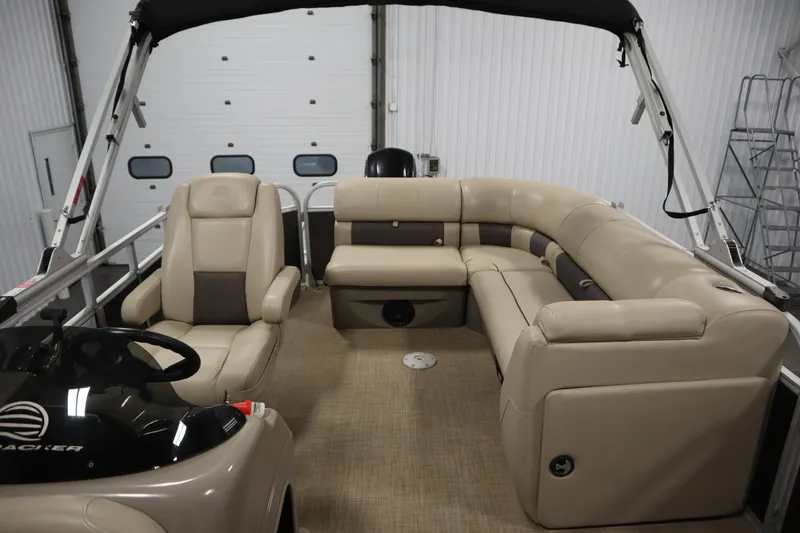 Slide: The Image of 2022 Tracker 20 Party Barge DLX interior with beige seating and steering console. - 35