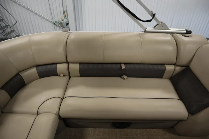 Slide: The Image of 2022 Tracker 20 Party Barge DLX, beige and brown cushioned seating, indoor setting. - 37