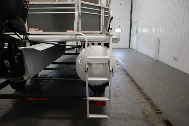 Slide: The Image of 2022 Tracker 20 Party Barge DLX pontoon boat rear view with ladder in garage. - 44